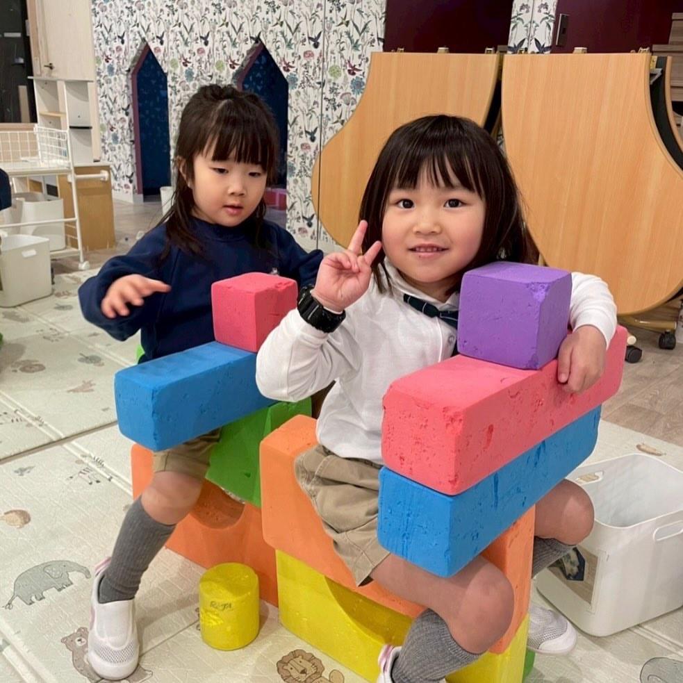 大きなカラーブロックを積み上げて、友だちと一緒に遊びをつくり出す園児たち