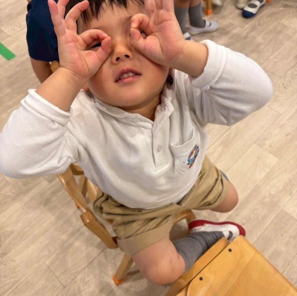 両手で双眼鏡をつくって遊ぶ園児。日々の何気ない瞬間にも好奇心があふれる園の様子
